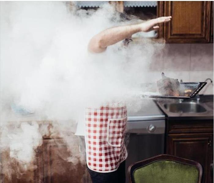 smoking fire food in a kitchen, man in an apron