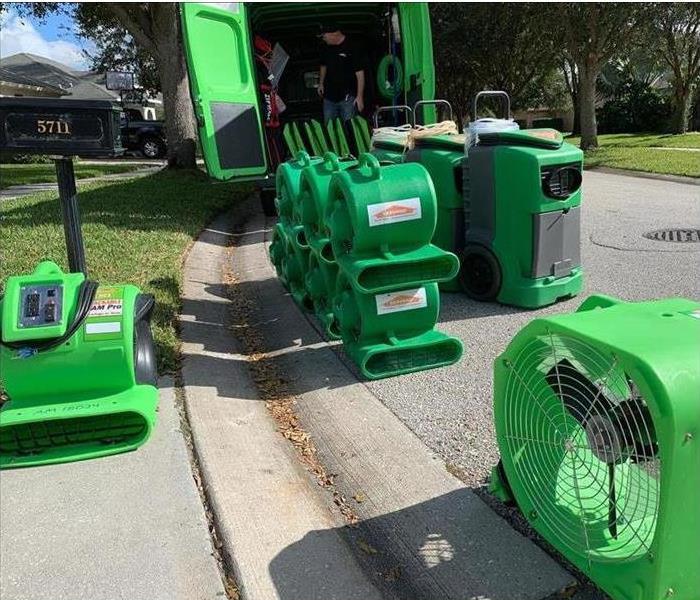 SERVPRO water damage equipment being unloaded from a van on a street