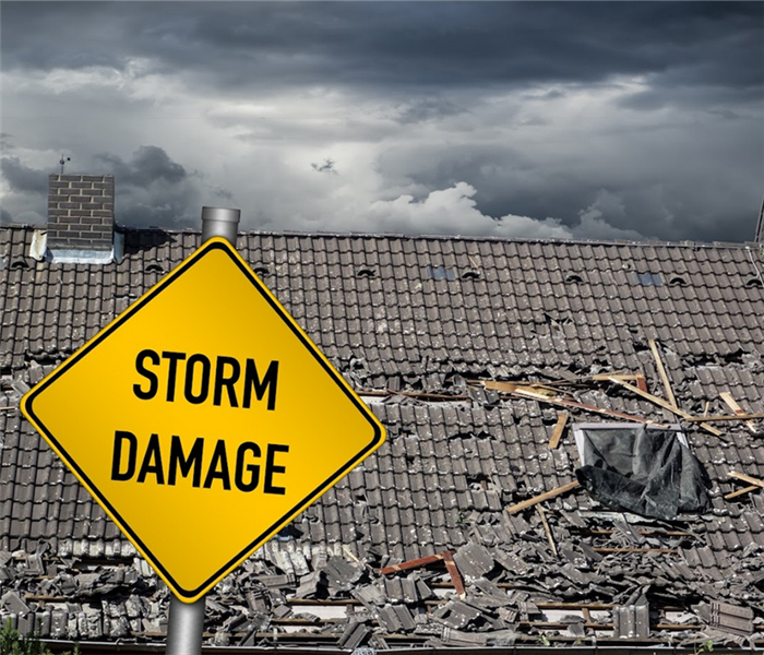 a storm damaged house with a yellow storm damage sign in front of it