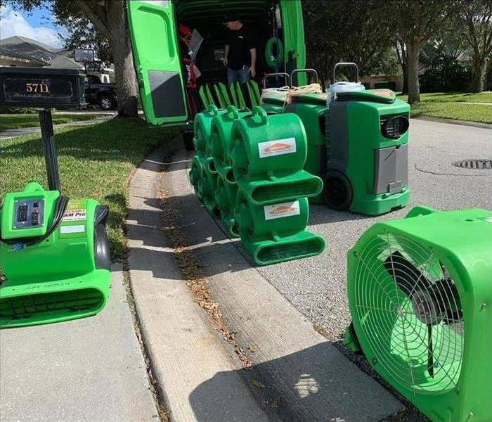 SERVPRO water damage equipment being unloaded from a van on a street